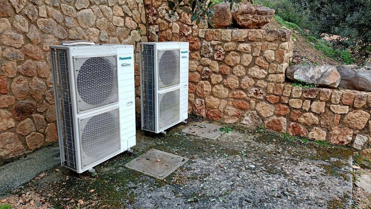 Dos bombas de calor exteriores junto a un muro de piedra seca en una finca de Mallorca, instalación de JSL