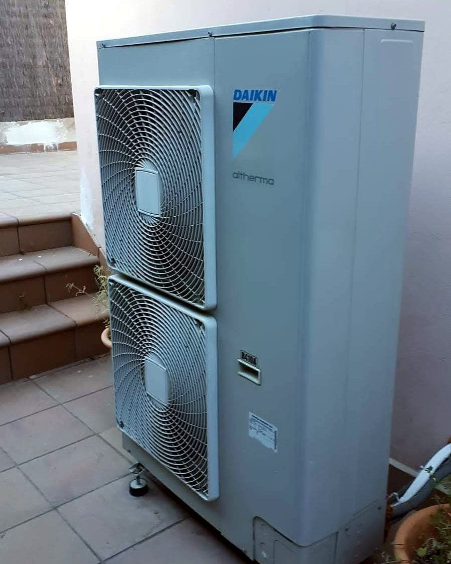 Unidad exterior de bomba de calor Daikin Altherma de dos ventiladores en el patio embaldosado de una vivienda de Mallorca