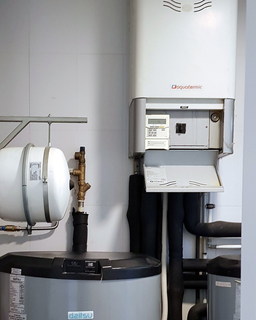 Sala técnica de aerotermia con depósito de agua caliente Daitsu, vaso de expansión, módulo hidráulico con su control y tubería aislada, instalada por JSL en Mallorca