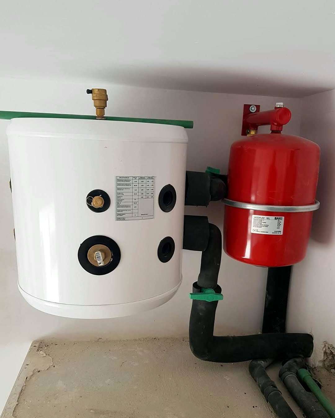 Depósito con purgador y vaso de expansión rojo, con las tuberías aisladas, en el cuarto técnico de una vivienda de Mallorca