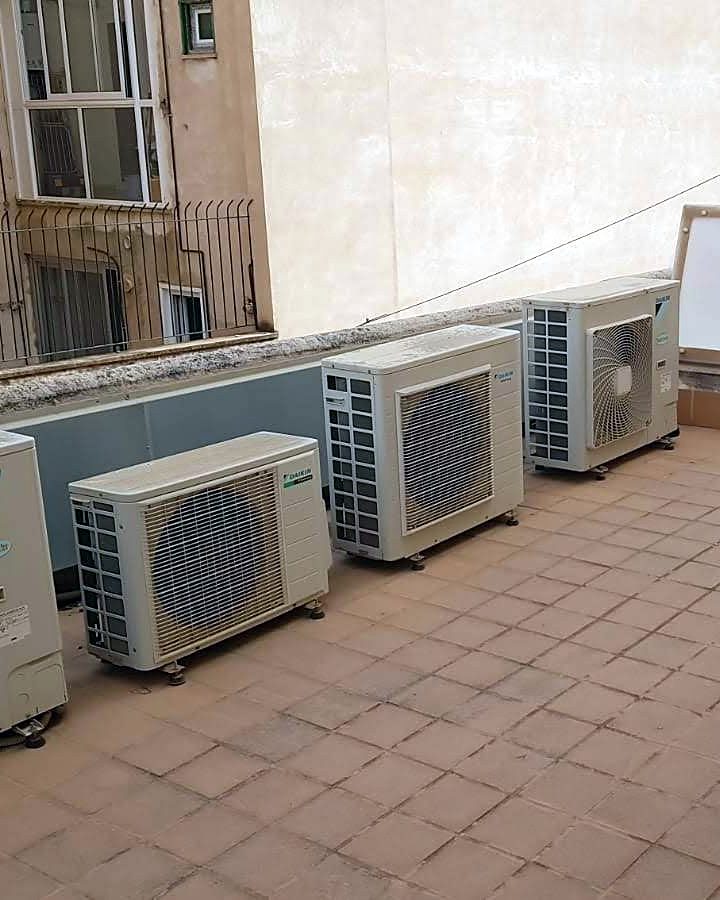 Varias unidades exteriores de aire acondicionado Daikin sobre soportes antivibración en la terraza embaldosada de un edificio de Mallorca