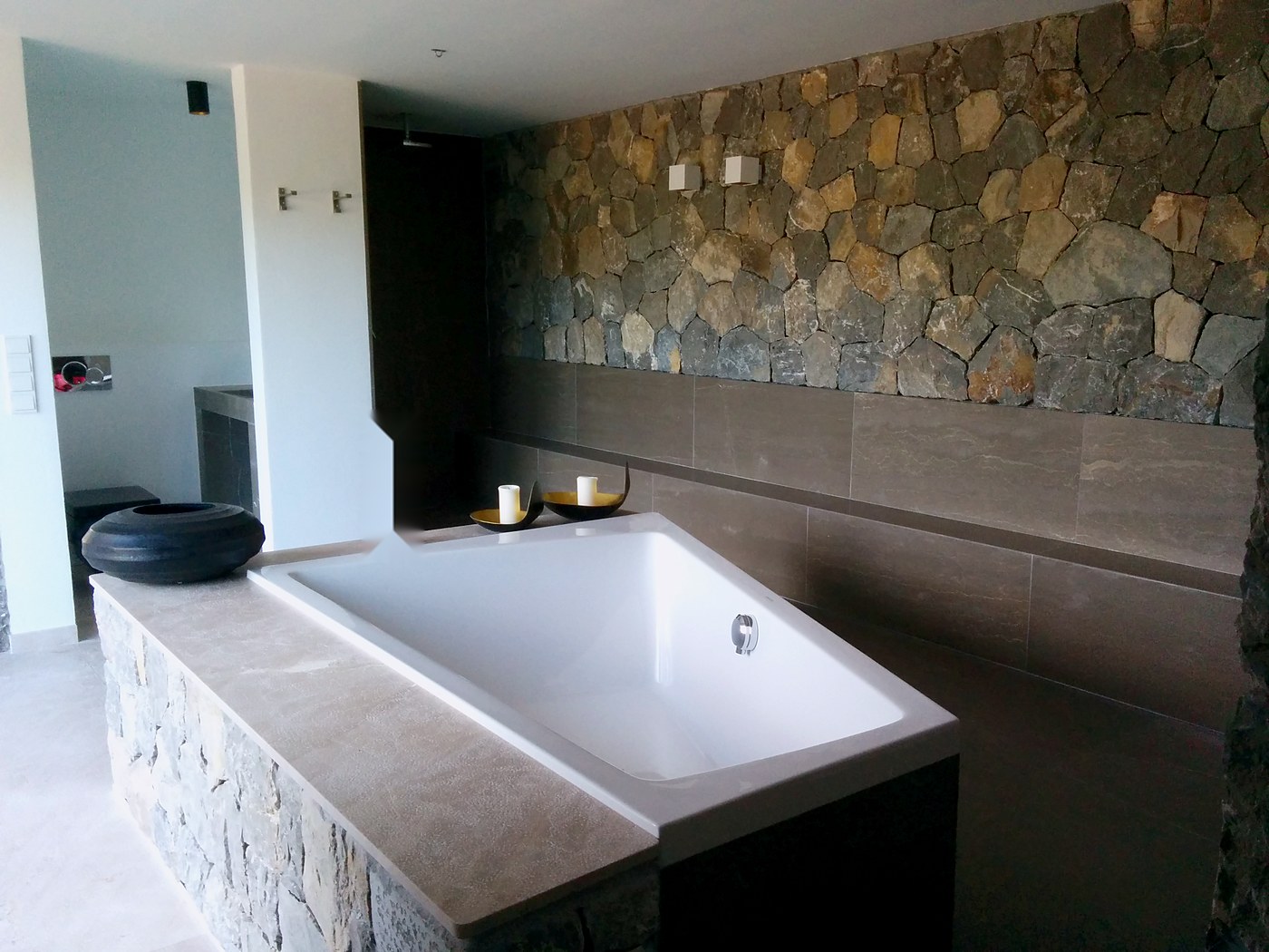Baño de villa con bañera empotrada y pared de piedra, una casa de Mallorca con instalaciones nuestras