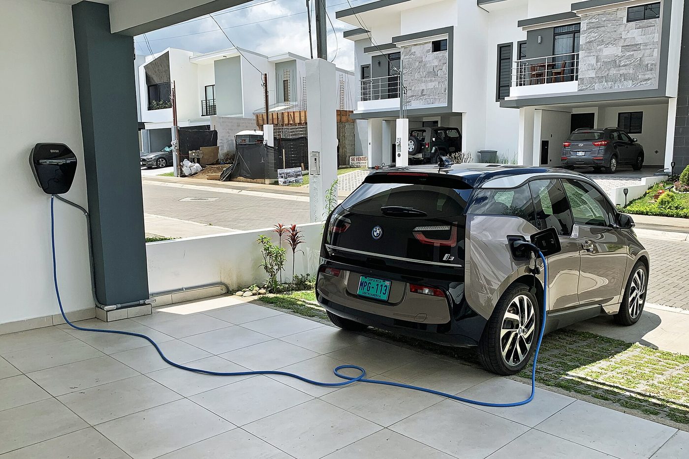 Wandladestation lädt ein Elektroauto in der Einfahrt eines Wohnhauses