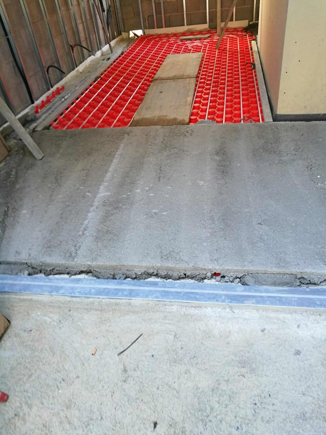 Transition between the red underfloor heating and the grey screed during the Casa Llucmajor build, an installation by JSL in Mallorca
