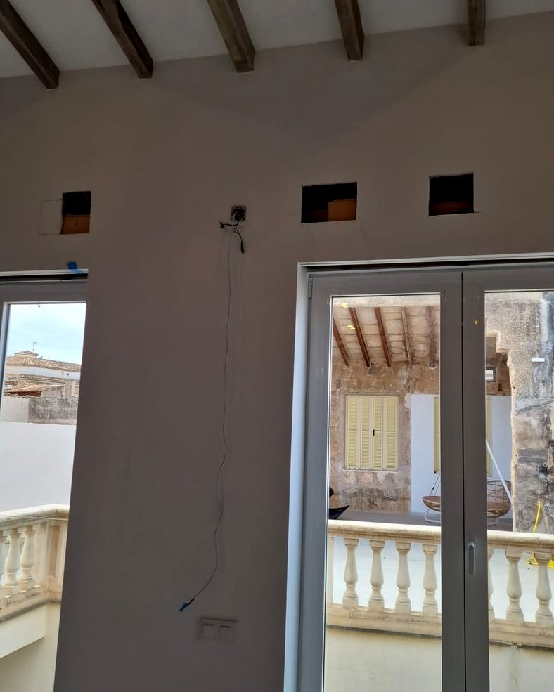 Ventanas y balconera de una vivienda en Mallorca, con vigas de madera en el techo