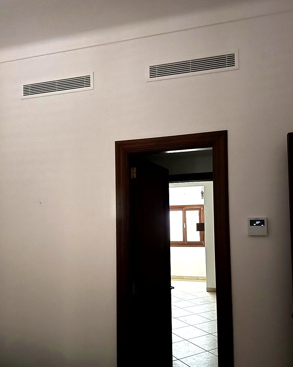 Zwei Zuluftgitter einer Kanalklimaanlage über einer Tür, daneben das Thermostat, eingebaut von JSL auf Mallorca