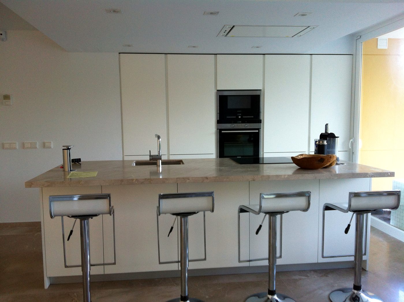 Cocina moderna con isla y taburetes en la Villa de Port d'Andratx, instalación de JSL en Mallorca