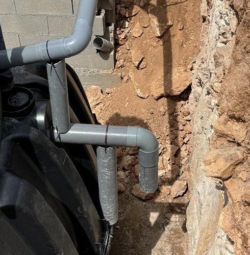 Conexiones de PVC que entran en el depósito de polietileno de una depuradora, junto a la zanja, montadas por JSL en Mallorca