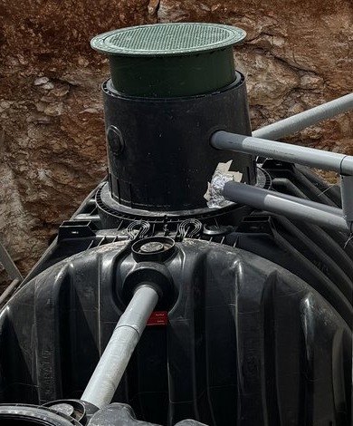 Cuello de registro con tapa verde sobre el depósito de polietileno de una depuradora, con sus tuberías conectadas, montado por JSL en Mallorca