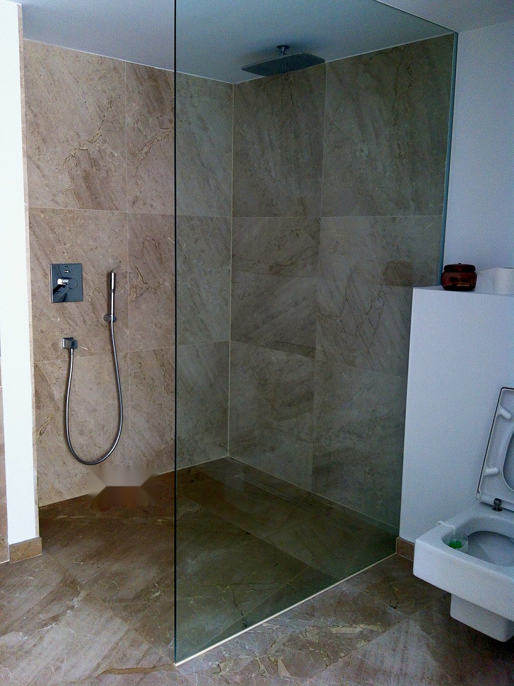 Ducha de obra con mampara de vidrio y grifería empotrada en mármol, una instalación nuestra en Mallorca