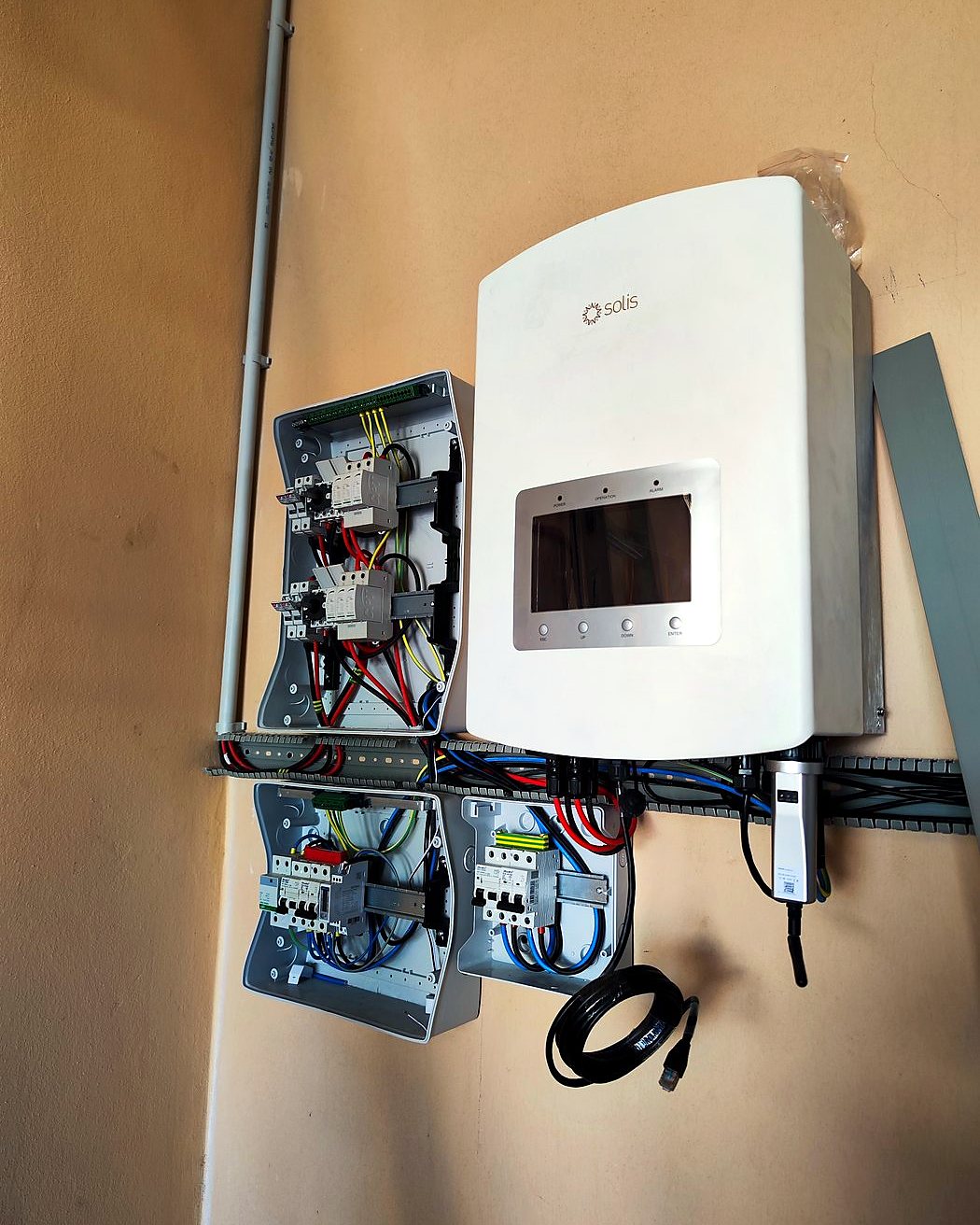 Inversor Solis con sus cajas de protecciones en una pared ocre, instalado por JSL en Mallorca