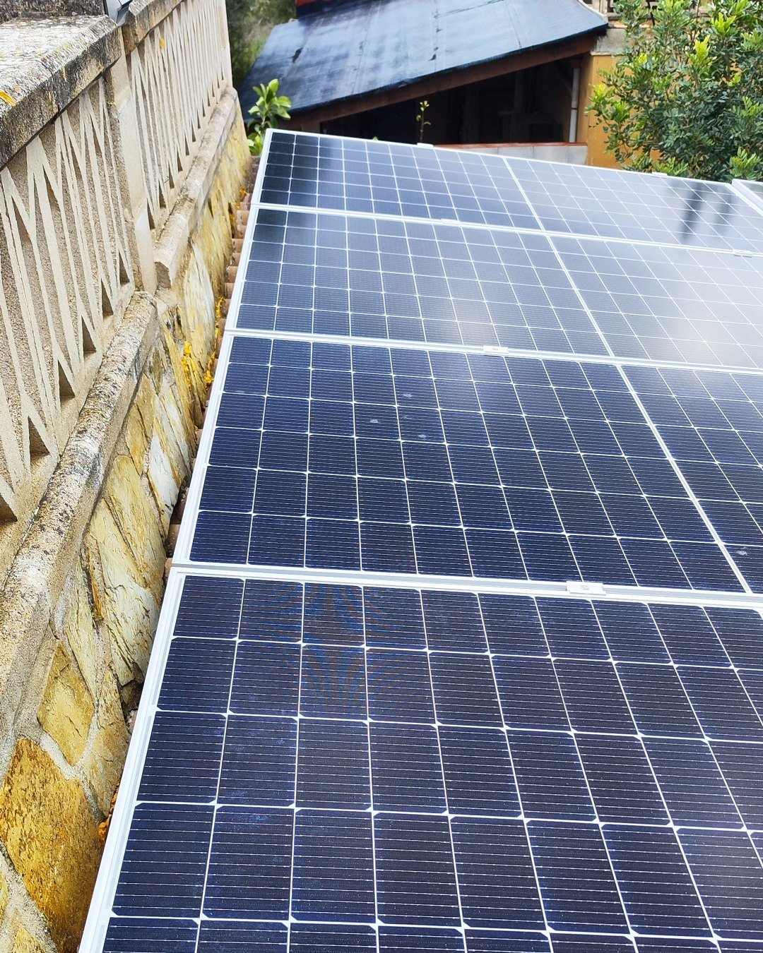 Fila de placas solares sobre una cubierta junto a un muro con balaustrada, instalación de JSL en Mallorca