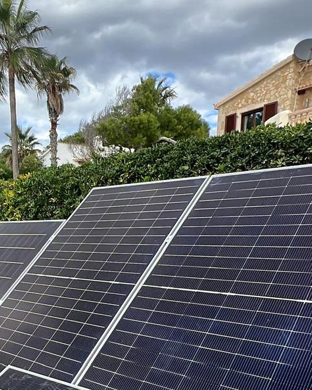 Placas solares sobre estructura en el suelo en el jardín de una villa de Mallorca, con palmeras, montadas por JSL