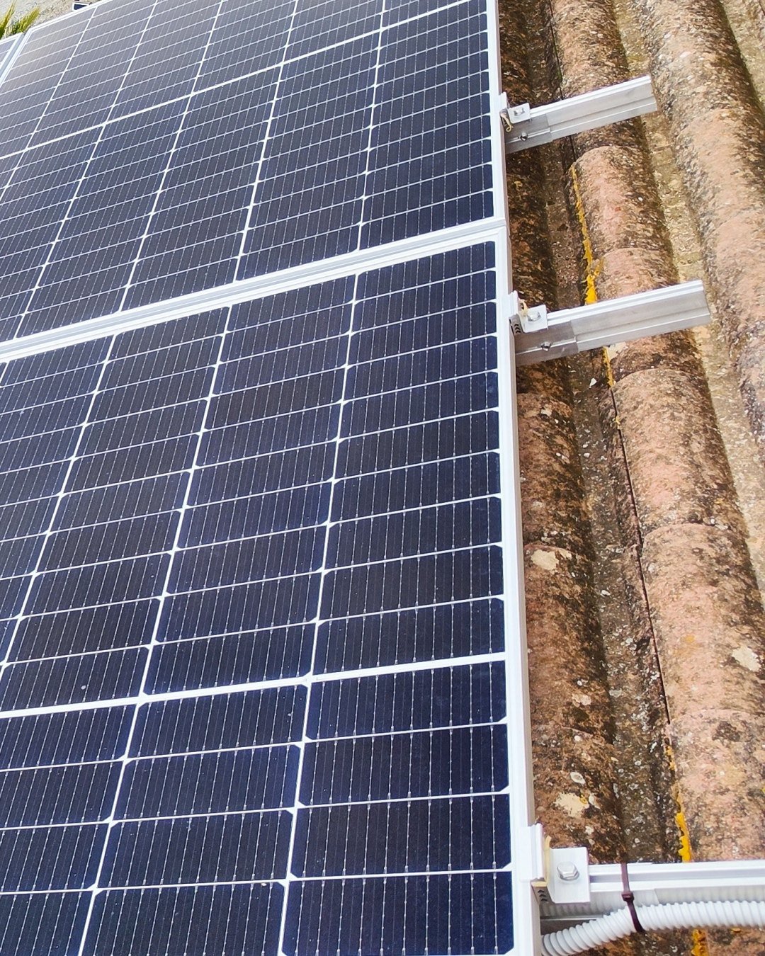 Placas solares sobre un tejado de teja rodeado de arbolado, una instalación nuestra en Mallorca