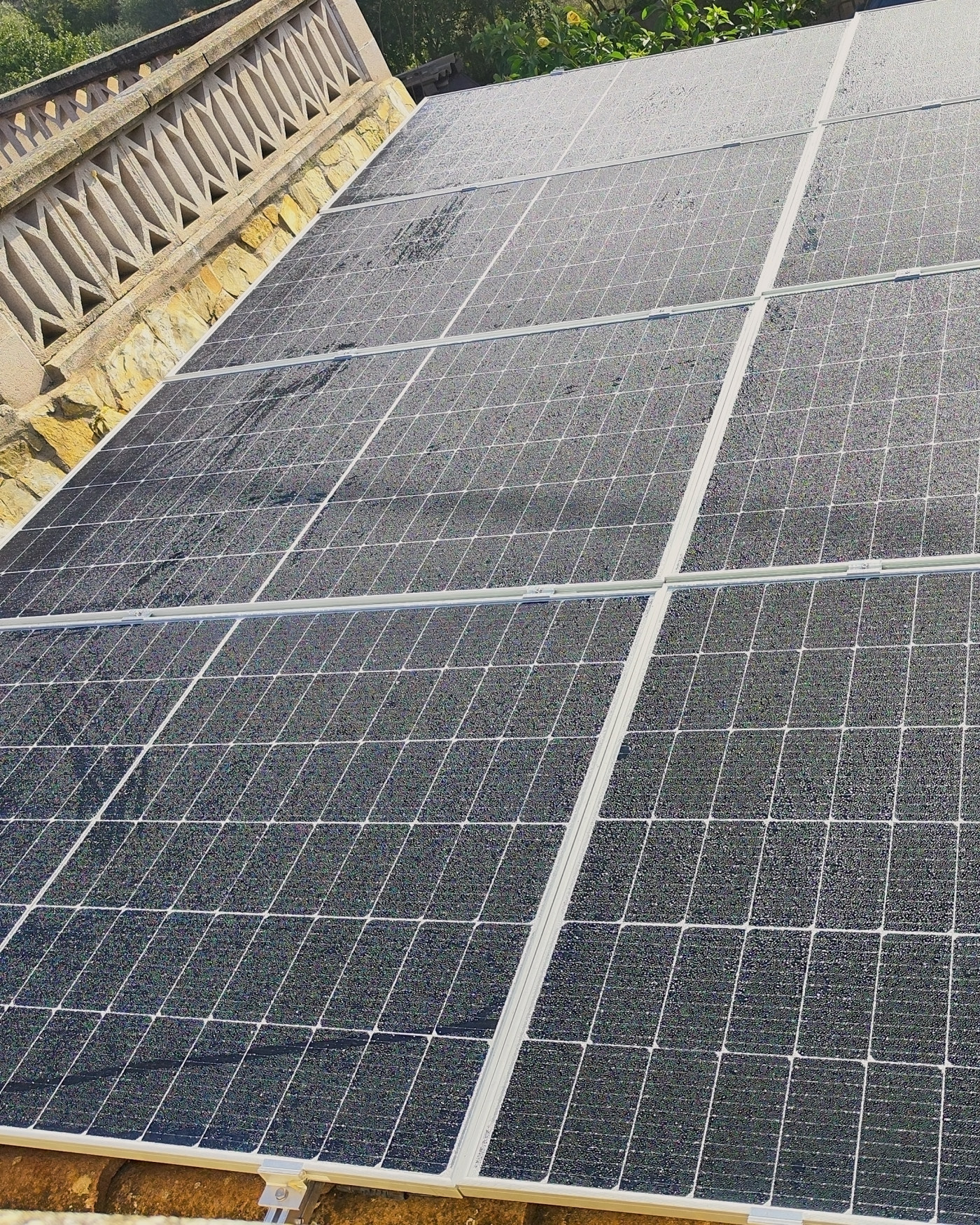 Placas solares sobre un tejado con balaustrada de piedra entre pinos, una instalación nuestra en Mallorca