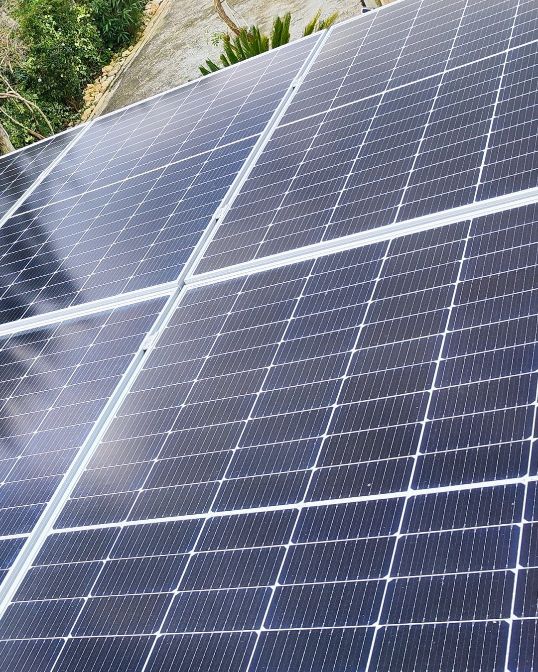 Placas solares coplanares sobre un tejado de teja rodeado de vegetación en el interior de Mallorca