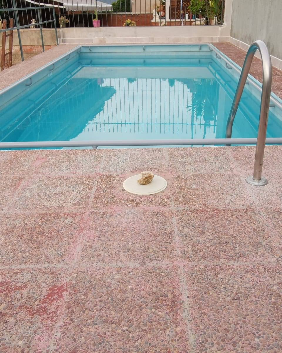 Piscina de una vivienda en Mallorca, con su escalera de acero inoxidable y el limpiafondos