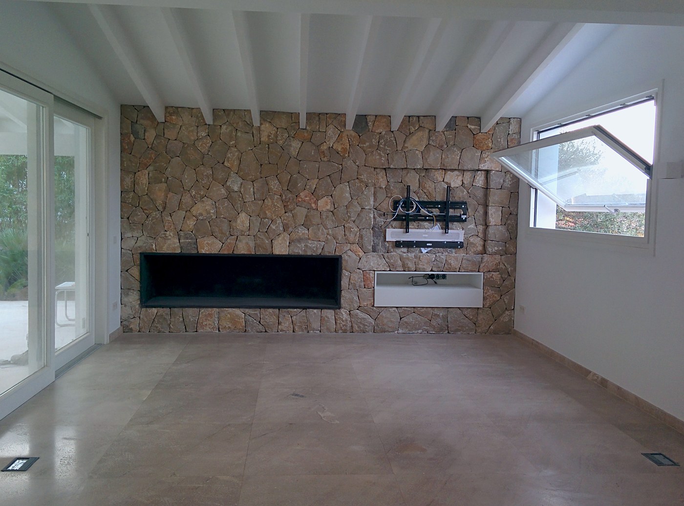 Salón de villa con pared de piedra y chimenea, una casa de Mallorca con instalaciones nuestras
