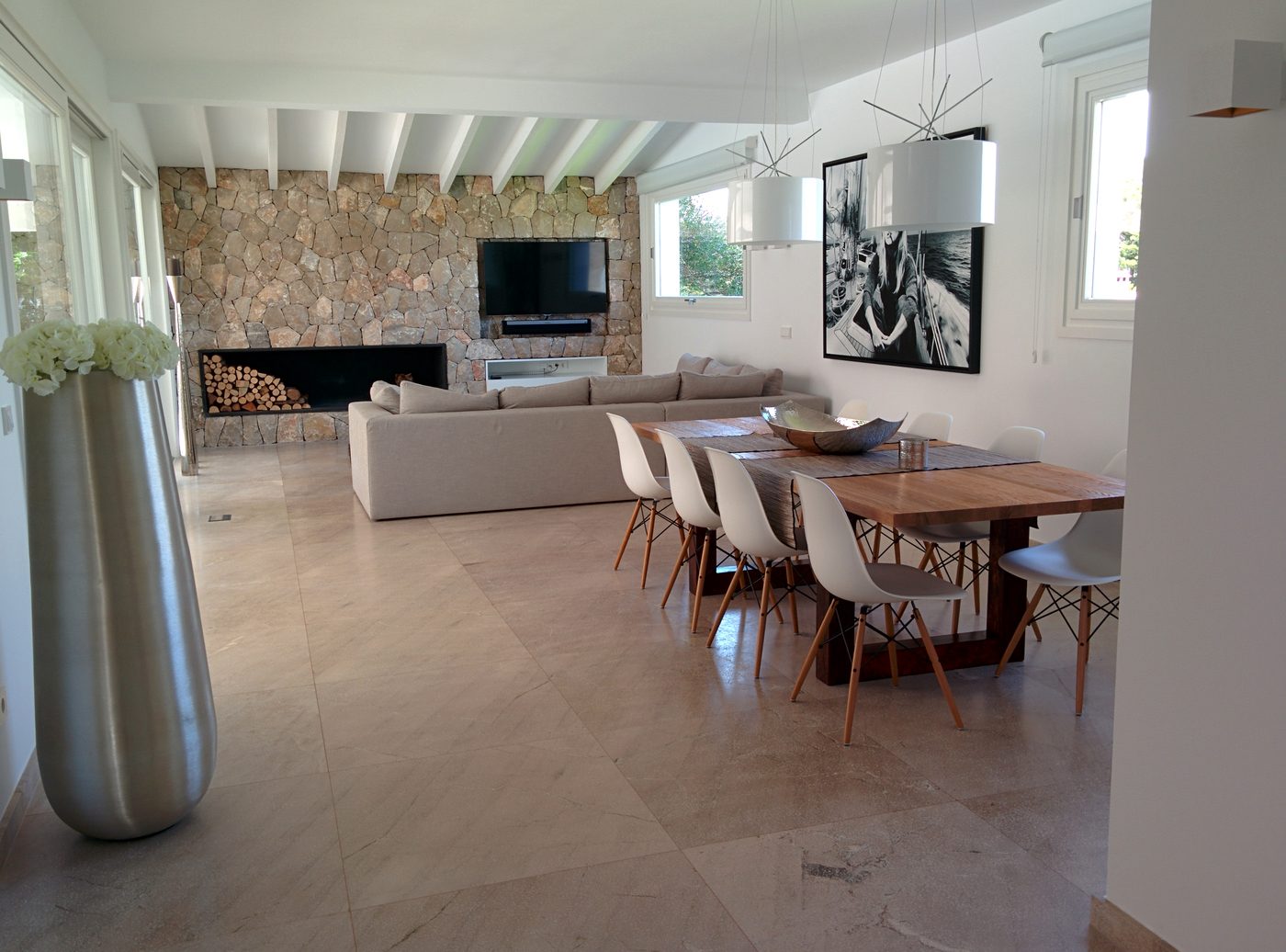 Renoviertes Wohnzimmer einer Villa mit mallorquinischer Steinwand und Kamin, Installationen von JSL auf Mallorca