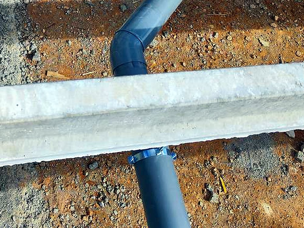 Tubería de saneamiento de PVC con su codo bajando entre las viguetas del forjado sanitario, en una obra de JSL en Mallorca