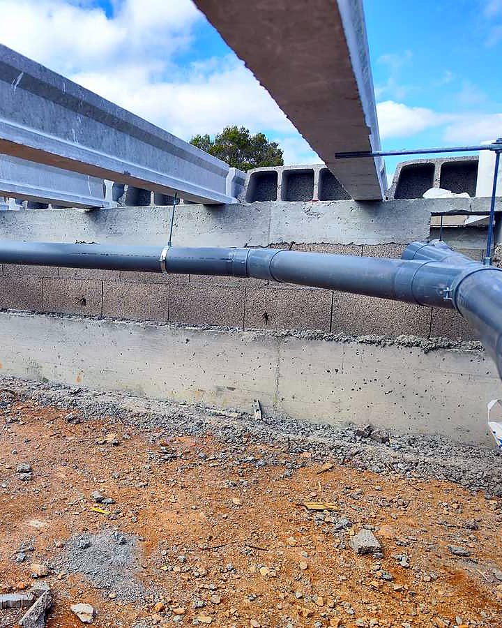 Colector de PVC colgado bajo las viguetas del forjado sanitario de una casa en construcción, montado por JSL en Mallorca