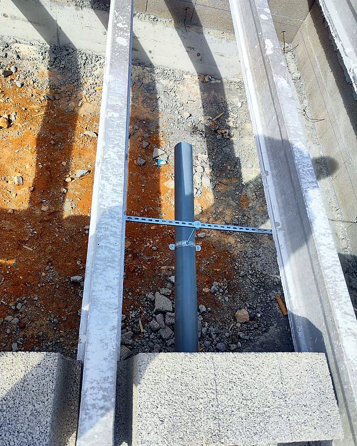 Canalización de PVC hacia la depuradora entre las viguetas del forjado sanitario, sujeta con su abrazadera, en una obra de JSL en Mallorca