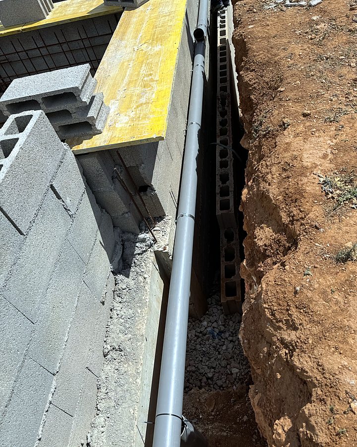Canalización de PVC hacia la depuradora por la zanja entre el muro de bloques y el terreno, en una obra de JSL en Mallorca
