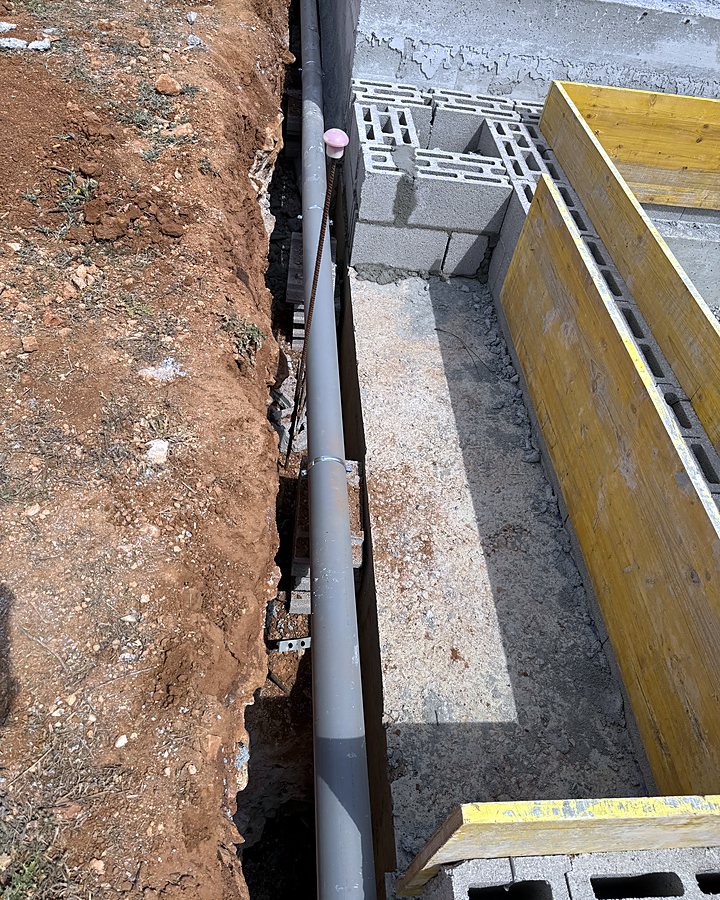 Canalización de PVC hacia la depuradora, tendida en la zanja junto a la cimentación encofrada, en una obra de JSL en Mallorca