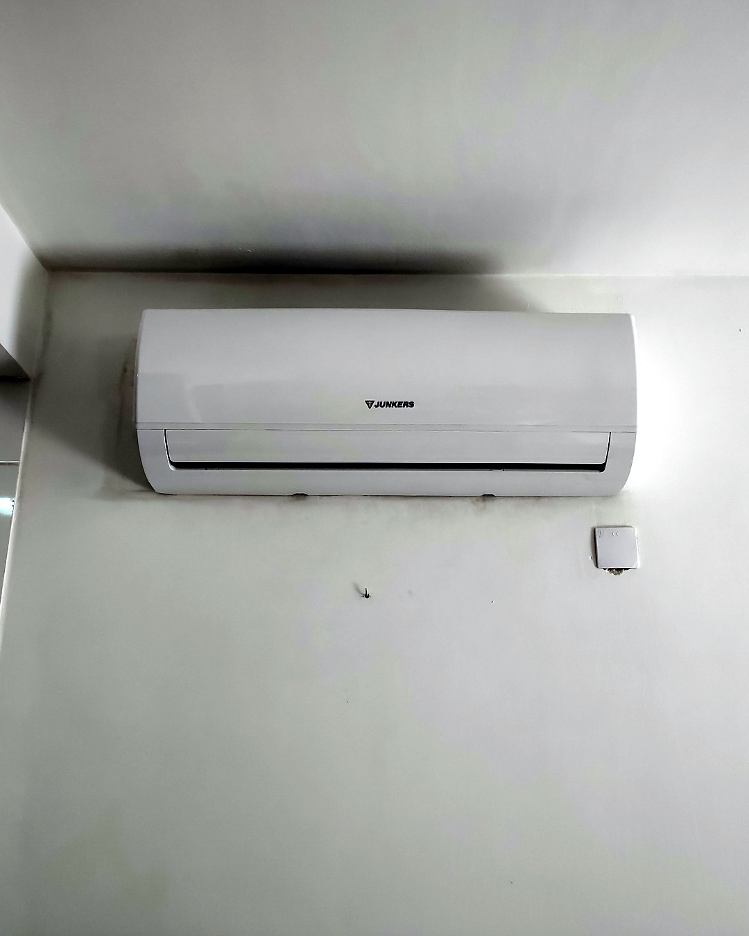Split de pared Junkers bajo el techo en una pared blanca, junto a un alicatado blanco, en una vivienda de Mallorca