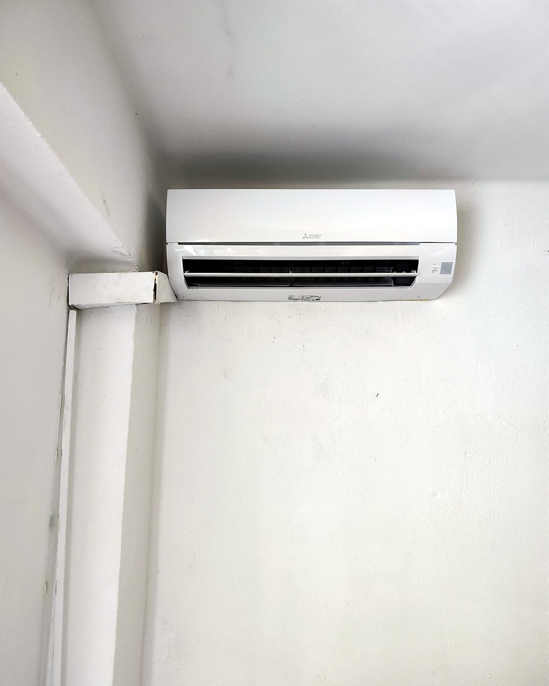 Split de pared Mitsubishi Electric en el rincón de una estancia, con la canaleta blanca bajando por la esquina, en una vivienda de Mallorca