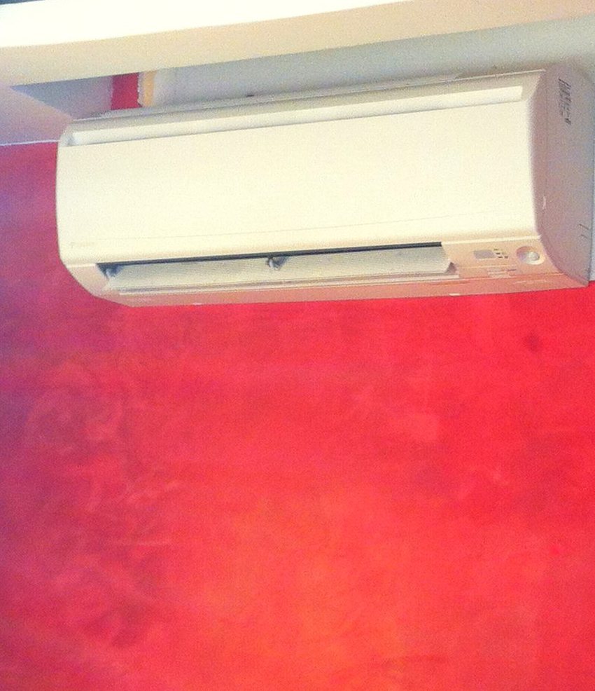 Split de pared montado sobre una pared estucada en rojo, bajo una repisa, instalado por JSL en Mallorca