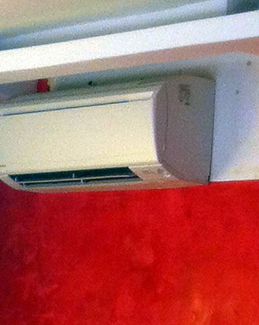 Split de pared bajo un falso techo, sobre una pared estucada en rojo, instalado por JSL en Mallorca