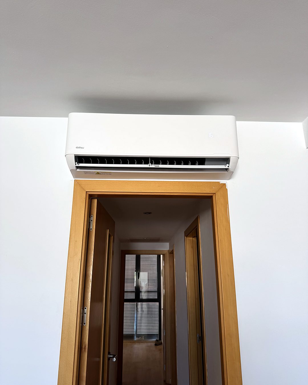 Split de pared Daitsu instalado sobre la puerta de un dormitorio que da al pasillo, en una vivienda de Mallorca climatizada por JSL